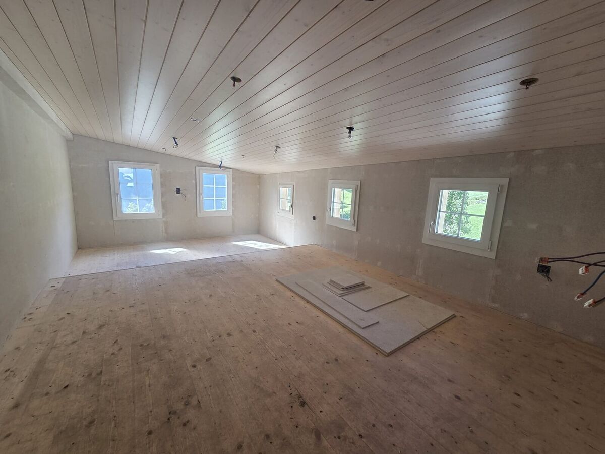 Ausgebauter Raum mit Holzdecke und neuen Fenstern